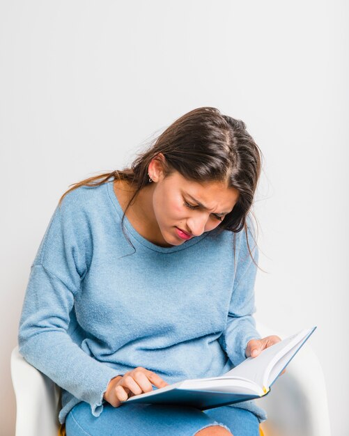 Jeune fille brune assise en lisant un livre
