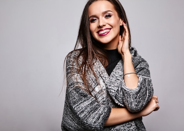 jeune fille brune dans des vêtements de chandail chaud décontracté sur fond gris avec maquillage de soirée et lèvres colorées