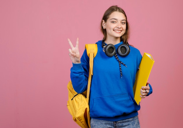 Jeune fille brune debout souriante montrant la salutation de paix