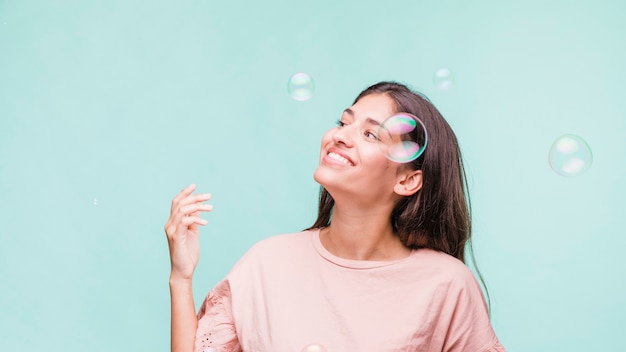 Jeune fille brune jouant avec des bulles de savon