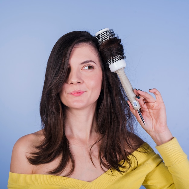 Photo gratuite jeune fille brune posant avec une brosse à cheveux