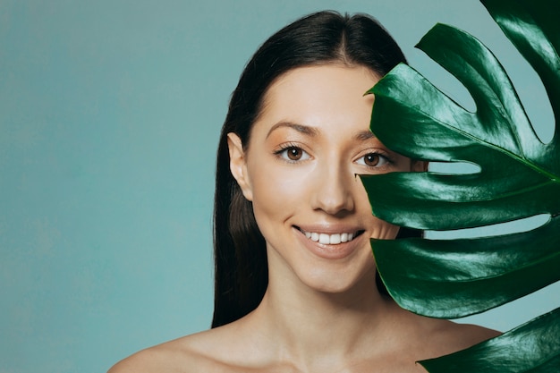 Jeune fille brune posant avec des feuilles exotiques