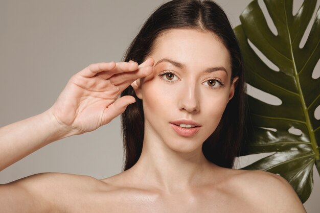 Jeune fille brune posant avec des feuilles exotiques