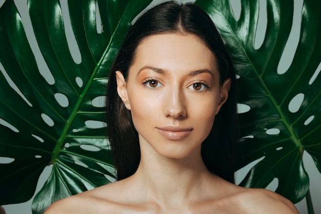 Jeune fille brune posant avec des feuilles exotiques