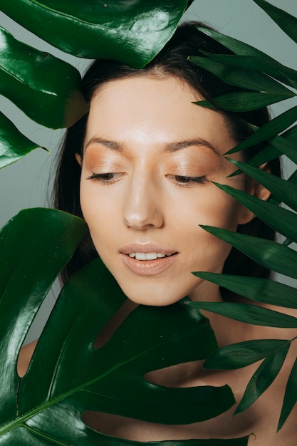 Jeune fille brune posant avec des feuilles exotiques