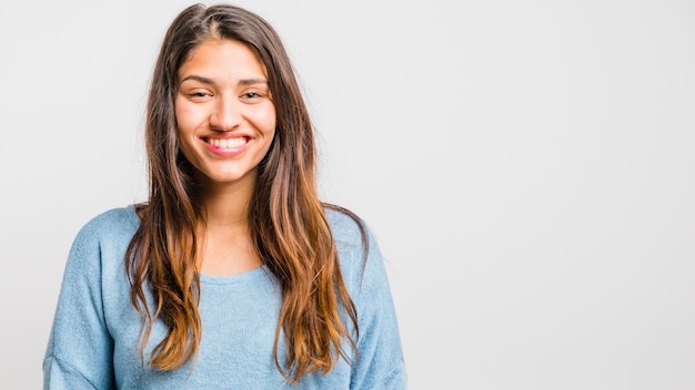 Jeune fille brune posant avec un pull bleu