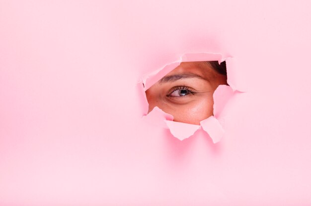 Jeune fille brune posant à travers un trou de papier