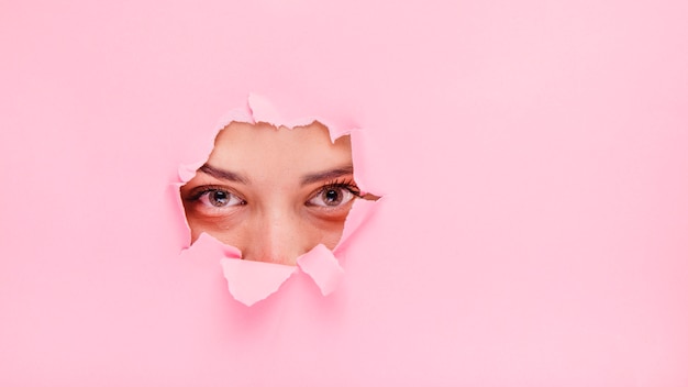 Jeune fille brune posant à travers un trou de papier