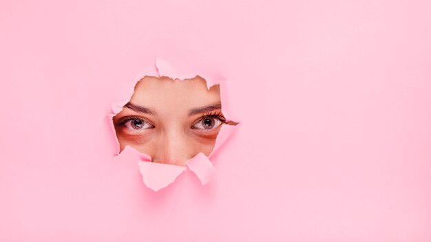 Jeune fille brune posant à travers un trou de papier