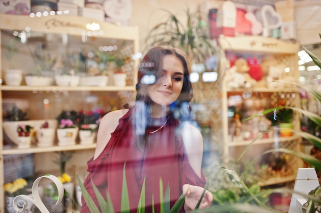 Photo gratuite jeune fille brune en rouge acheter des fleurs au magasin de fleurs