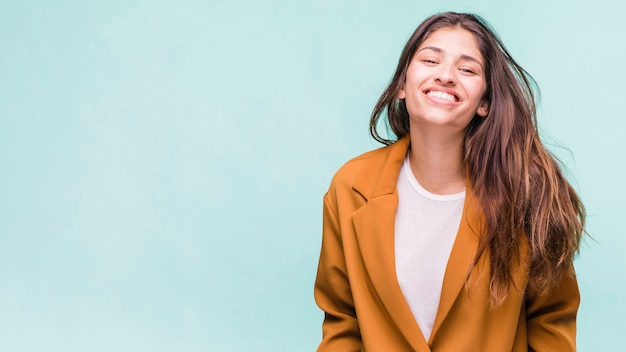 Jeune fille brune souriante posant avec manteau