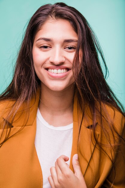 Jeune fille brune souriante posant avec manteau