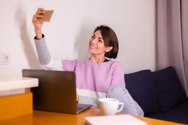 Jeune fille caucasienne femme dans la chambre sur le canapé regarde la caméra du téléphone mobile