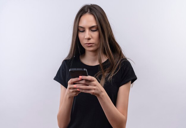 Jeune fille caucasienne portant le numéro de t-shirt noir sur téléphone sur blanc isolé