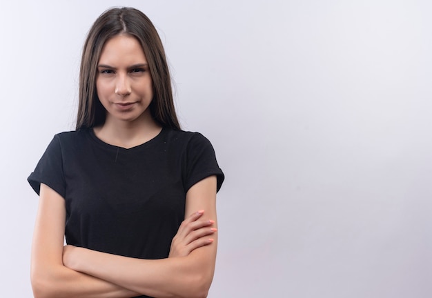 Jeune fille caucasienne portant un t-shirt noir, croisant les mains sur un mur blanc isolé