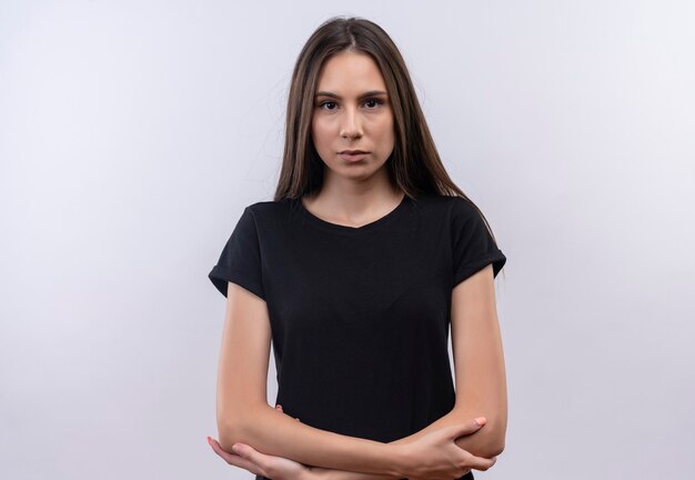 Jeune fille caucasienne portant un t-shirt noir, croisant les mains sur un mur blanc isolé