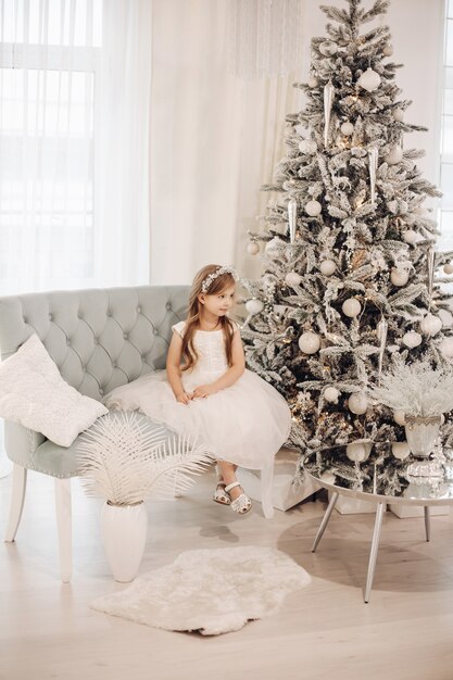 Jeune fille caucasienne en robe blanche pose pour la caméra dans l'atmosphère de Noël