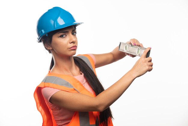 La jeune fille charmante le constructeur avec l'outil de mesure sur le mur blanc