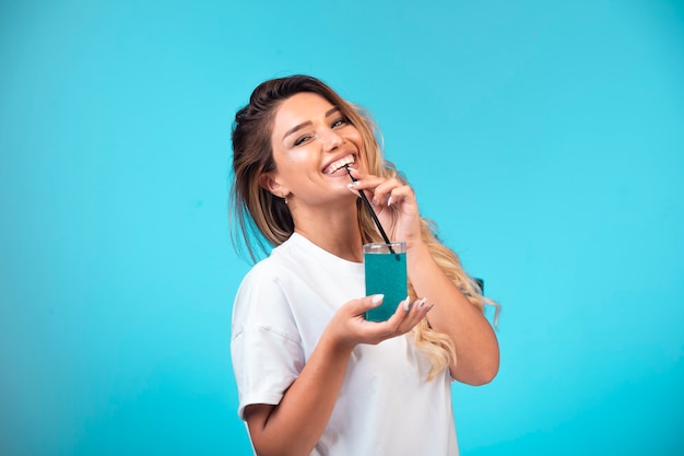 Jeune fille en chemise blanche, boire un cocktail bleu et s'amuser.