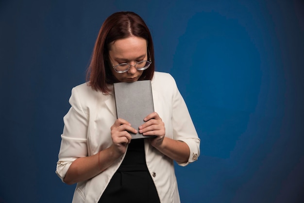 Jeune fille en chemise noire mettant un livre sous son menton.