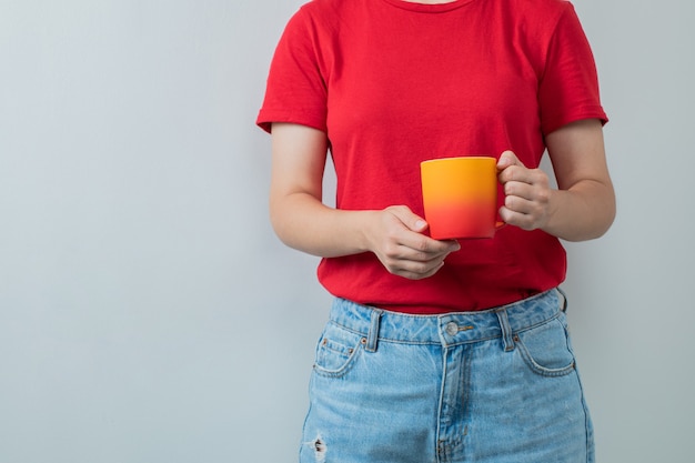 Jeune fille en chemise rouge tenant une tasse de boisson