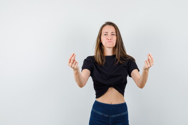 Jeune fille en chemisier noir, pantalon gesticulant avec les doigts et à la triste