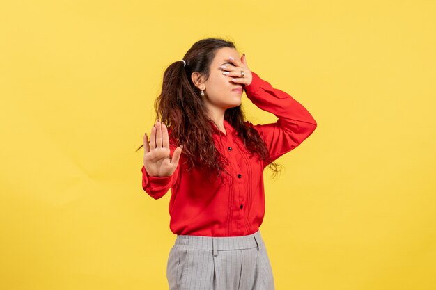 jeune fille en chemisier rouge couvrant son visage sur jaune