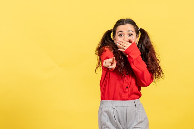 jeune fille en chemisier rouge pointant avec visage excité sur jaune