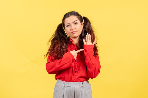 jeune fille en chemisier rouge posant sur jaune