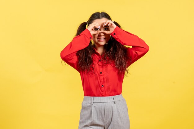 jeune fille en chemisier rouge posant sur jaune