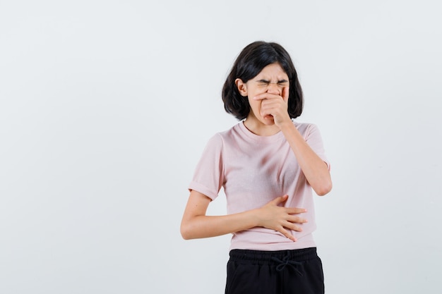 Jeune fille couvrant la bouche avec la main tout en bâillant en t-shirt rose et pantalon noir et à la somnolence