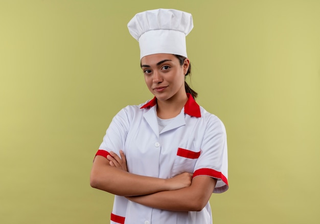 Jeune fille de cuisinier caucasien confiant en uniforme de chef croise les bras et regarde la caméra isolée sur fond vert avec espace de copie