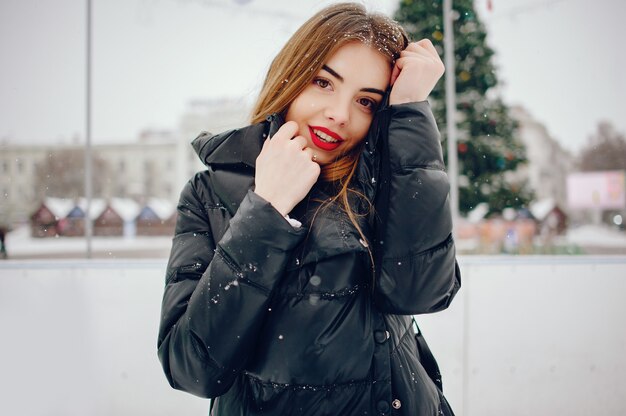 Jeune fille dans un pull blanc, debout dans un parc d'hiver