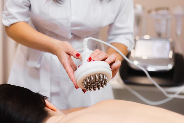 La jeune fille dans le salon spa reçoit un massage du dos et de la nuque, se trouve dans la table de cosmétologie, détendue et apprécie le processus