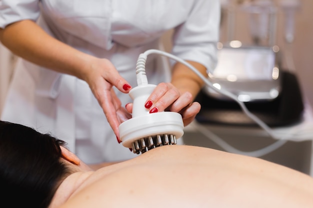 La jeune fille dans le salon spa reçoit un massage du dos et de la nuque, se trouve dans la table de cosmétologie, détendue et apprécie le processus