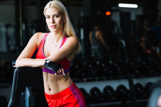 Jeune fille debout dans la salle de gym sombre