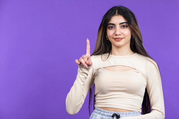 Jeune fille debout fils fond violet et pointer le doigt vers le haut Photo de haute qualité