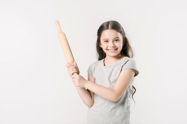 Jeune fille debout avec rouleau à pâtisserie en studio