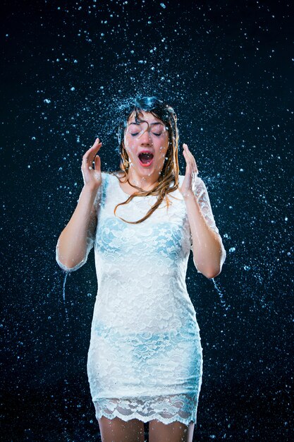 jeune fille debout sous l'eau courante