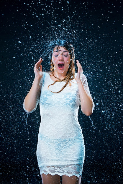 jeune fille debout sous l'eau courante