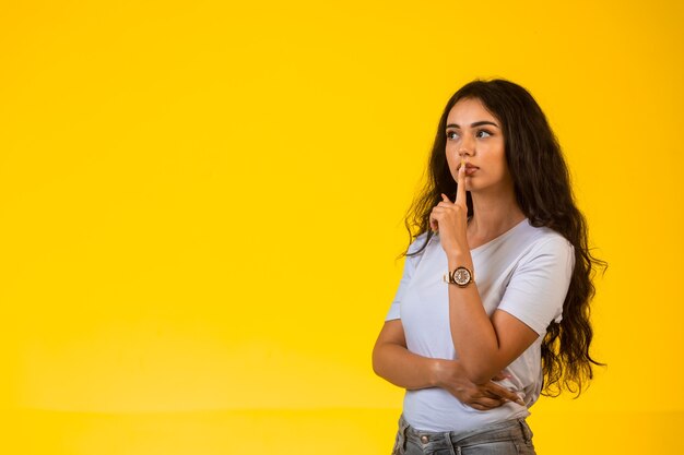 Jeune fille donne un signe de silence d'une manière romantique et regarde secrètement.