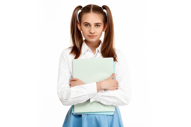 Jeune fille émotionnelle en uniforme posant, isolé sur mur blanc