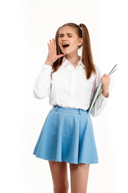 Jeune fille émotionnelle en uniforme posant, isolé sur mur blanc