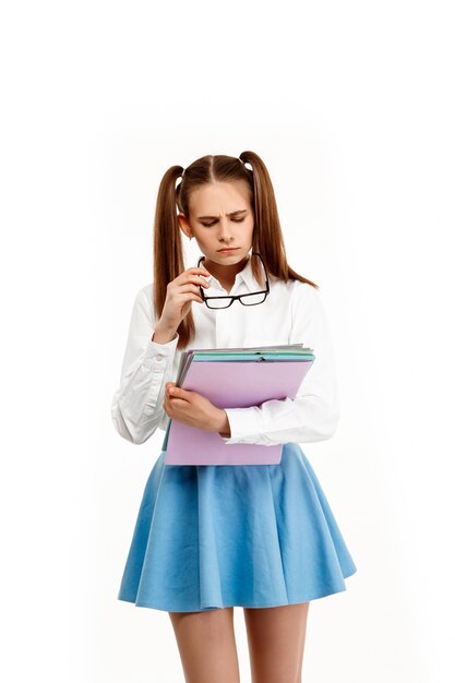 Jeune fille émotionnelle en uniforme posant, isolé sur mur blanc