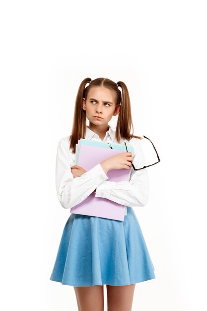 Jeune fille émotionnelle en uniforme posant, isolé sur mur blanc