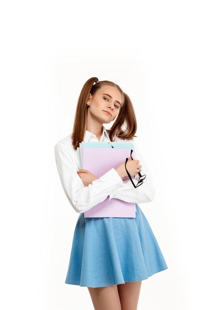 Jeune fille émotionnelle en uniforme posant, isolé sur mur blanc