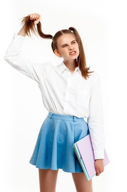 Jeune fille émotionnelle en uniforme posant, isolé sur mur blanc