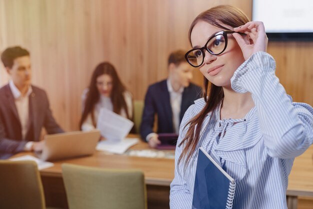 Jeune fille d'employé de bureau élégant attrayant dans des verres avec un ordinateur portable à la main