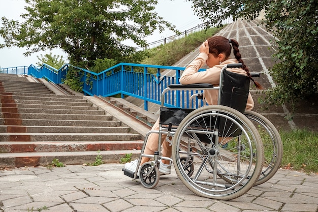 La jeune fille est assise dans un fauteuil roulant face à des difficultés seule, déprimée. le concept d'un fauteuil roulant, d'une personne handicapée, d'une vie pleine, d'une personne paralysée, handicapée, de soins de santé.