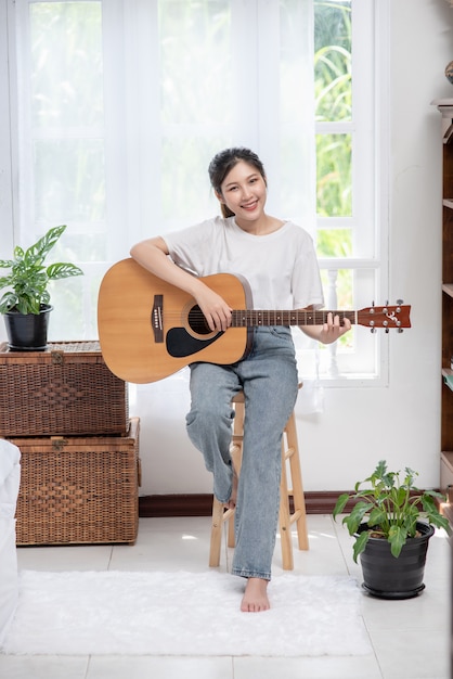 La jeune fille est assise et joue de la guitare sur la chaise.